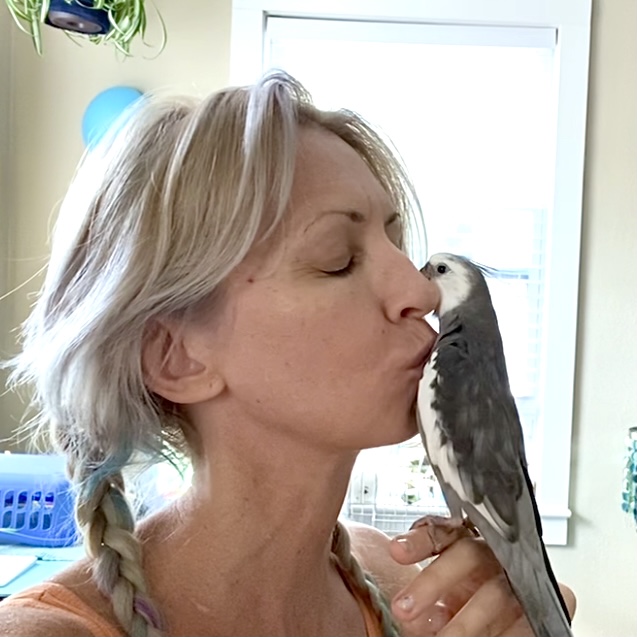 woman kisses cockatiel